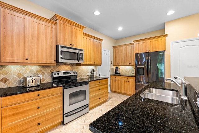 kitchen with backsplash, dark stone counters, sink, light tile patterned floors, and appliances with stainless steel finishes