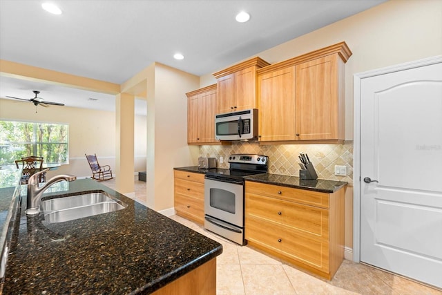 kitchen with dark stone counters, sink, light tile patterned flooring, appliances with stainless steel finishes, and ceiling fan