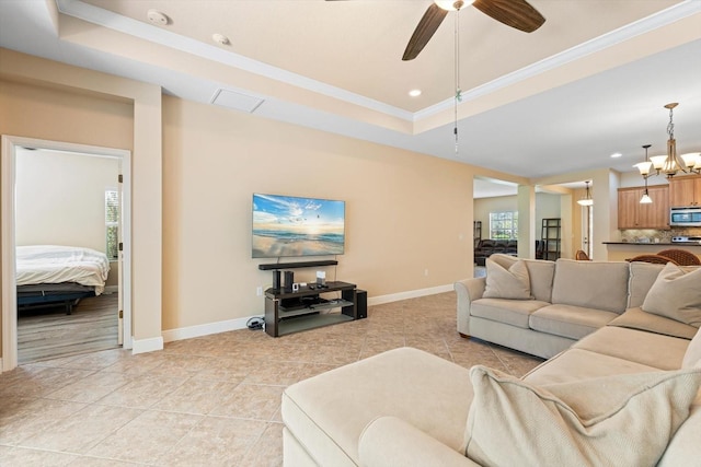 tiled living room with crown molding, ceiling fan with notable chandelier, and a raised ceiling