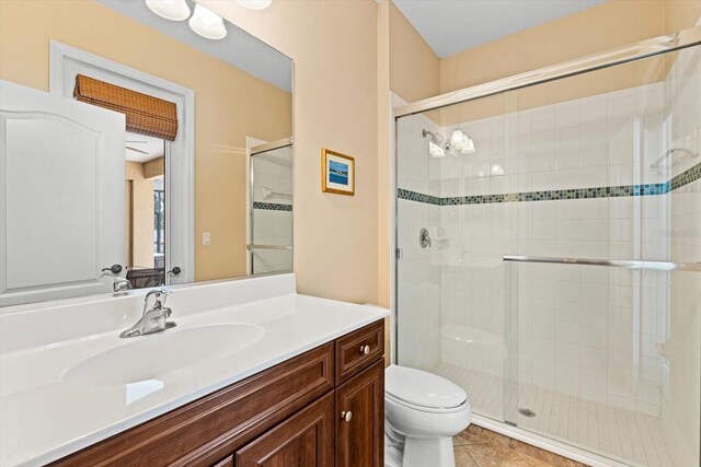 bathroom with a shower with door, toilet, tile patterned floors, and vanity