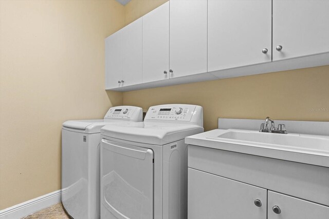 laundry room with sink, light tile patterned flooring, washer and dryer, and cabinets