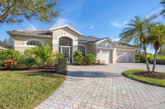 view of front of home with stucco siding, decorative driveway, a garage, and a tiled roof