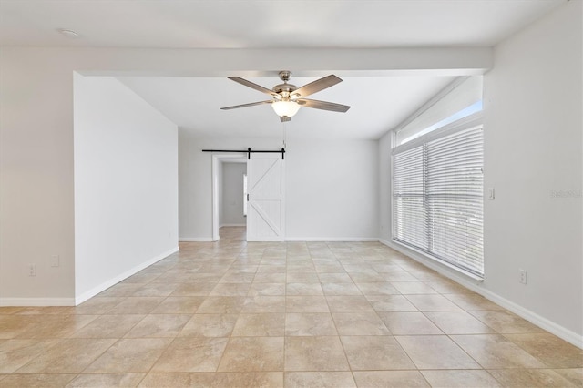 empty room featuring a barn door, ceiling fan, and light tile patterned floors