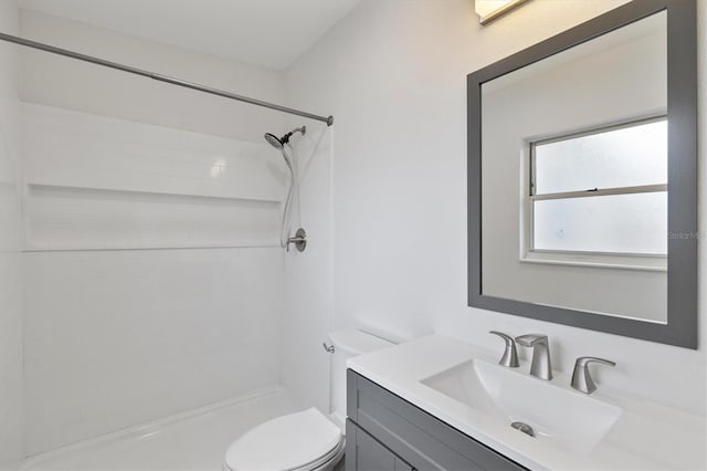 bathroom with a tile shower, vanity, and toilet