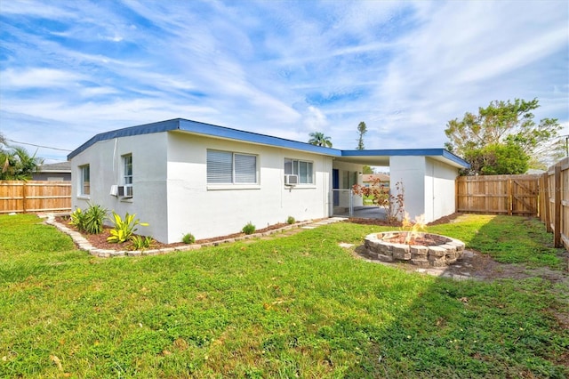 rear view of property featuring a lawn and an outdoor fire pit