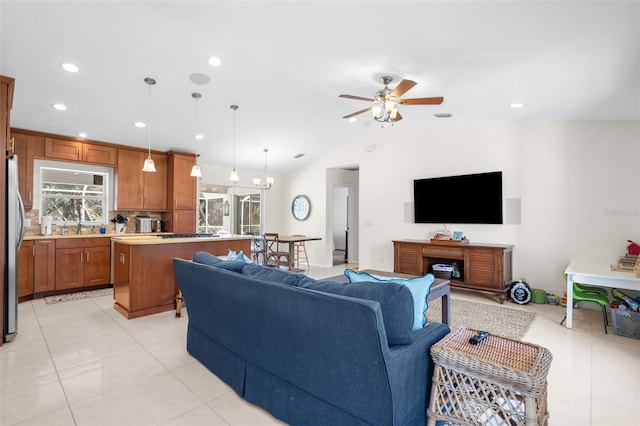 tiled living room with ceiling fan with notable chandelier, sink, and lofted ceiling