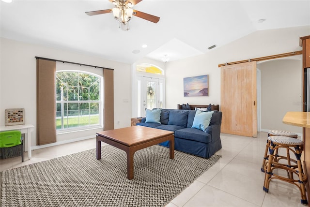 living room featuring a barn door, ceiling fan, light tile patterned floors, and vaulted ceiling