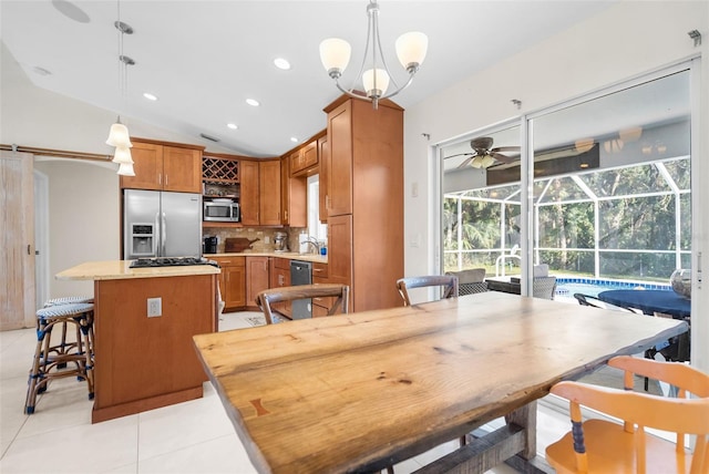 kitchen with a kitchen island, pendant lighting, vaulted ceiling, and appliances with stainless steel finishes