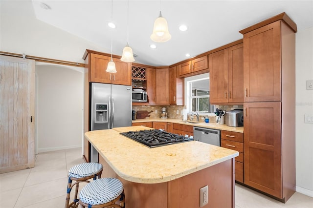 kitchen with sink, a center island, hanging light fixtures, a kitchen breakfast bar, and appliances with stainless steel finishes