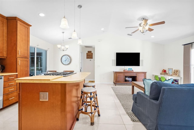 kitchen with vaulted ceiling, hanging light fixtures, a center island, stainless steel gas stovetop, and light tile patterned flooring