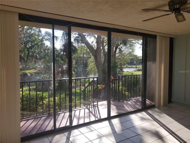 entryway with light tile patterned floors, a water view, and ceiling fan