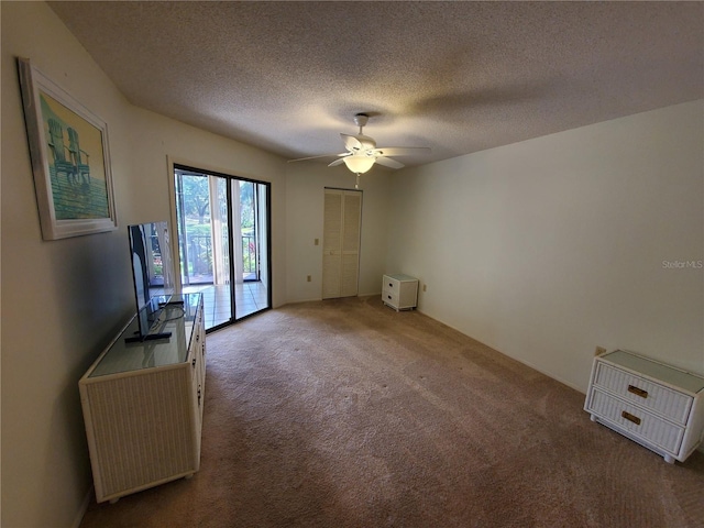 unfurnished living room featuring ceiling fan, carpet floors, and a textured ceiling