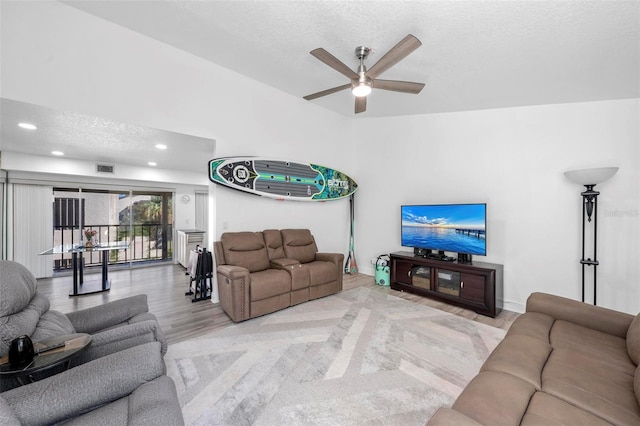 living room featuring light hardwood / wood-style floors, a textured ceiling, and ceiling fan