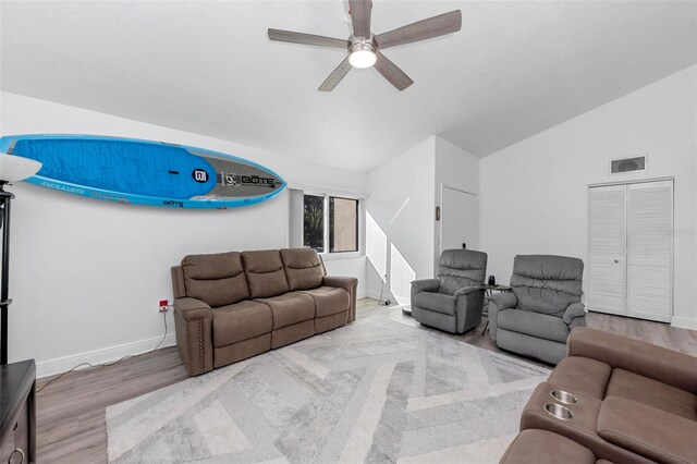 living room featuring light hardwood / wood-style floors, vaulted ceiling, and ceiling fan