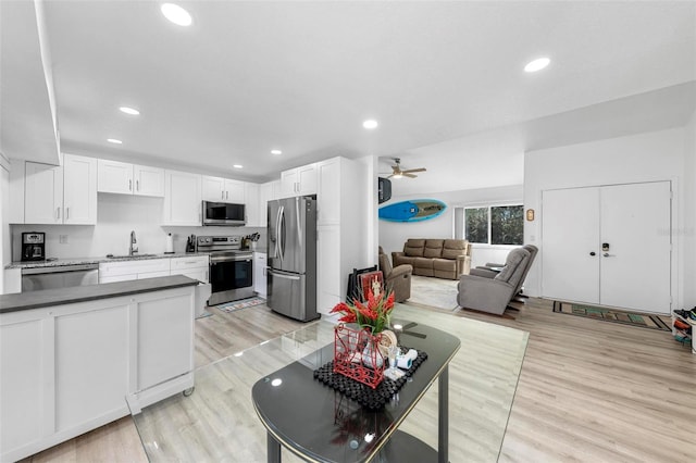 kitchen with appliances with stainless steel finishes, white cabinetry, sink, and light hardwood / wood-style floors