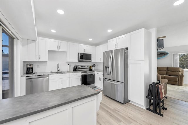 kitchen with appliances with stainless steel finishes, white cabinetry, sink, and light wood-type flooring