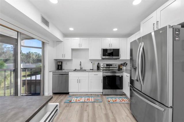 kitchen with light stone countertops, sink, light wood-type flooring, stainless steel appliances, and white cabinets