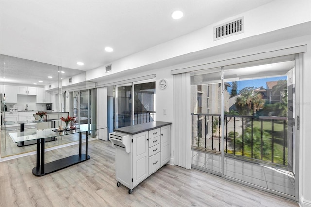 kitchen with light hardwood / wood-style flooring, white cabinetry, sink, and pendant lighting