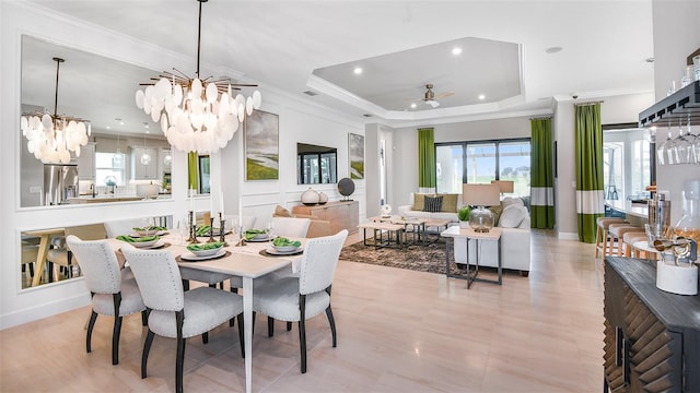 dining area featuring ceiling fan with notable chandelier, ornamental molding, and a tray ceiling