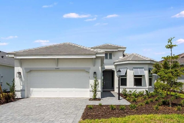 10442 Morning Mist, Sarasota, FL 34241 - prairie-style home with decorative driveway, an attached garage, a tiled roof, and stucco siding