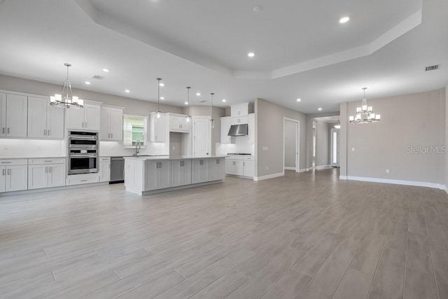 10442 Morning Mist, Sarasota, FL 34241 - unfurnished living room featuring a chandelier, light wood finished floors, recessed lighting, baseboards, and a raised ceiling