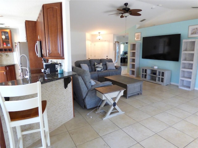 tiled living room with ceiling fan, sink, and vaulted ceiling