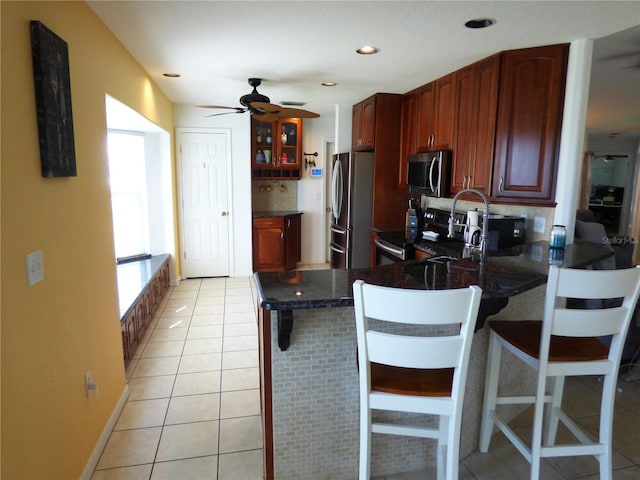 kitchen featuring a kitchen breakfast bar, kitchen peninsula, light tile patterned floors, and stainless steel appliances