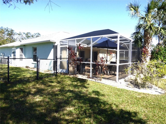 back of house featuring a yard and glass enclosure