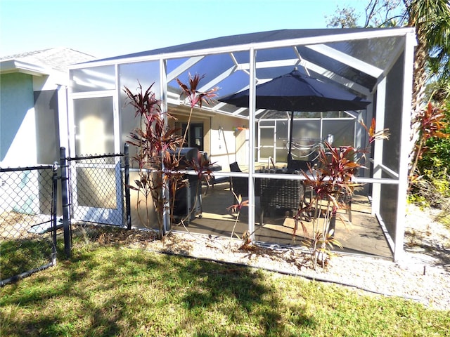 rear view of house featuring glass enclosure and a patio area