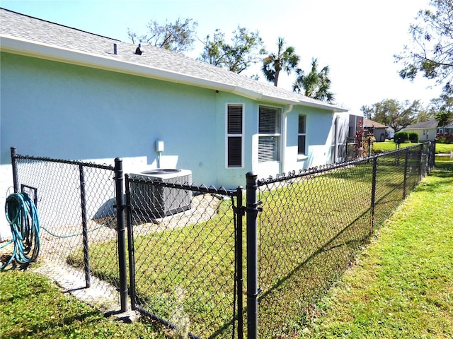 view of side of home with central AC and a lawn