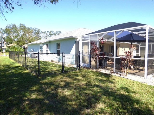 rear view of property featuring glass enclosure and a lawn