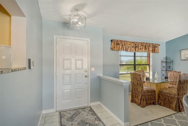 entryway featuring a notable chandelier, a textured ceiling, and light tile patterned floors