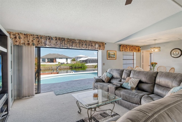 living room with a textured ceiling, vaulted ceiling, a water view, and carpet flooring