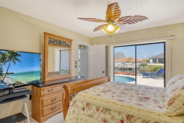 carpeted bedroom with a textured ceiling, access to exterior, a water view, and ceiling fan