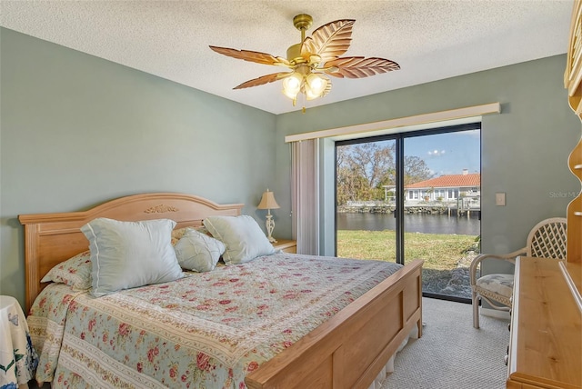 carpeted bedroom with access to outside, a textured ceiling, a water view, and ceiling fan