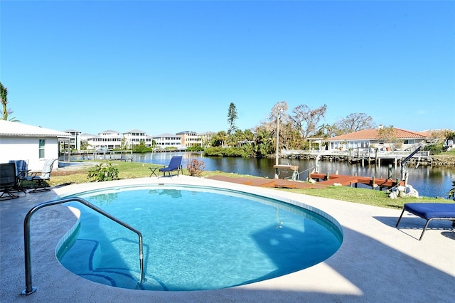 view of swimming pool with a patio area, a water view, and a lawn