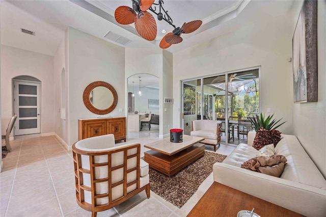 tiled living room with a tray ceiling, ceiling fan, and a high ceiling