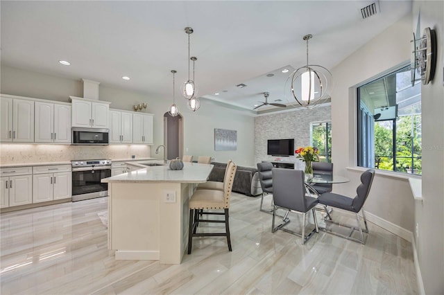 kitchen with sink, appliances with stainless steel finishes, white cabinetry, tasteful backsplash, and decorative light fixtures