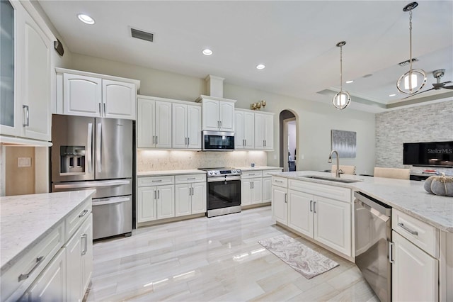 kitchen featuring pendant lighting, sink, white cabinetry, stainless steel appliances, and light stone counters