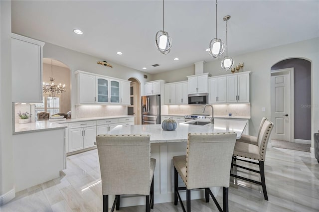 kitchen featuring sink, white cabinetry, tasteful backsplash, stainless steel appliances, and a kitchen island with sink