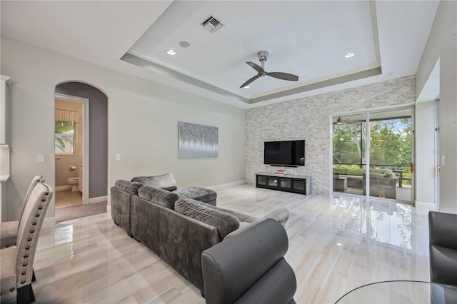 living room with a raised ceiling, crown molding, ceiling fan, and light hardwood / wood-style flooring