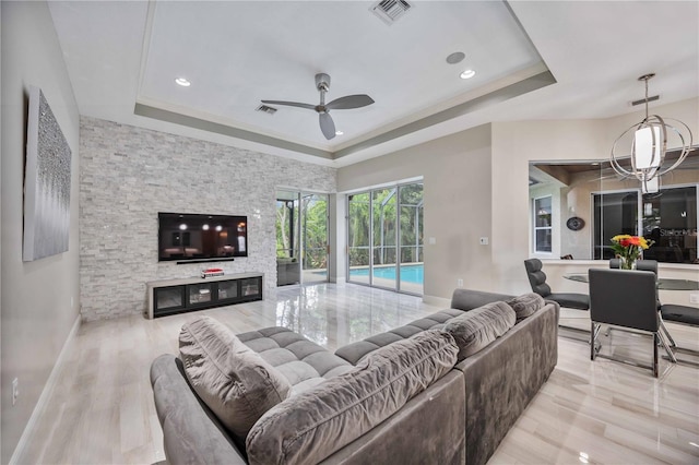 living room with a raised ceiling, crown molding, ceiling fan with notable chandelier, and light hardwood / wood-style flooring