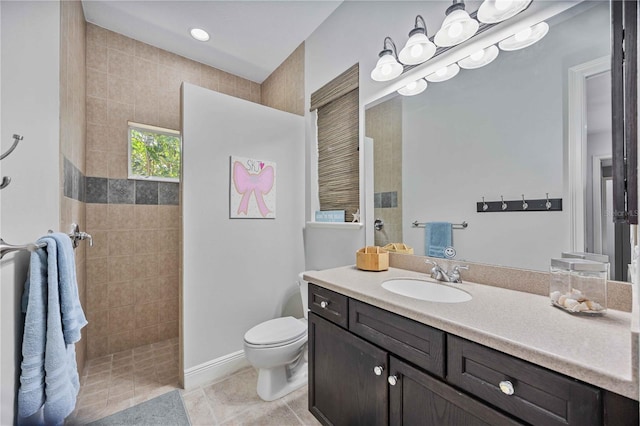 bathroom featuring vanity, tile patterned floors, toilet, and a tile shower