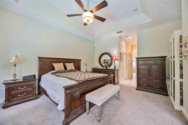 bedroom featuring ceiling fan, light colored carpet, and a raised ceiling