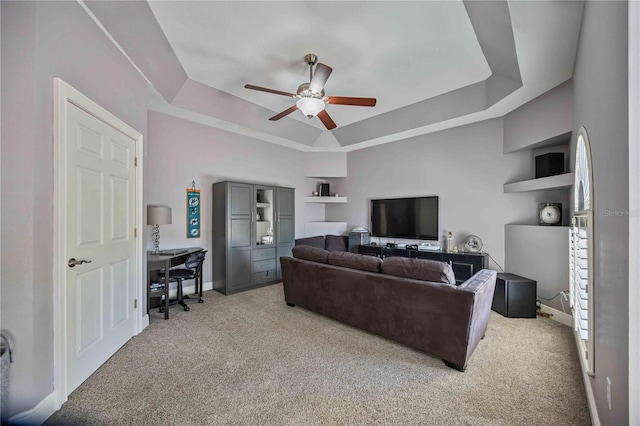 living room featuring ceiling fan, a tray ceiling, and light carpet