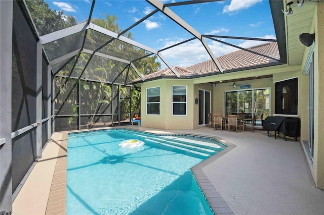 view of swimming pool with a grill, a patio area, and glass enclosure