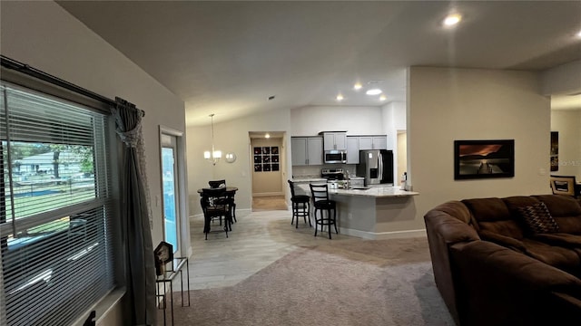 living room with light hardwood / wood-style flooring, a notable chandelier, and vaulted ceiling