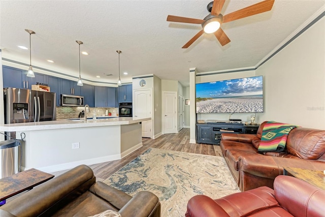 living room featuring ornamental molding, light hardwood / wood-style floors, a textured ceiling, and ceiling fan