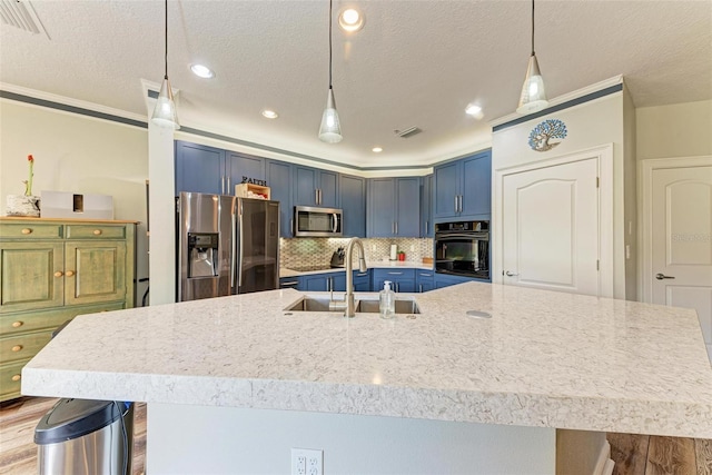 kitchen with wood-type flooring, appliances with stainless steel finishes, hanging light fixtures, decorative backsplash, and sink