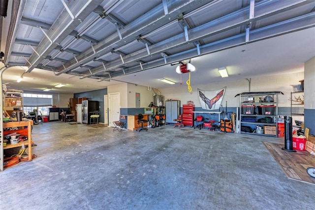 garage featuring electric panel, water heater, stainless steel refrigerator, and a garage door opener